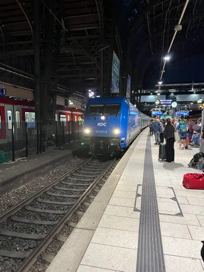 The blue RDC locomotive pulling the train, its lights shining bright in the darkness