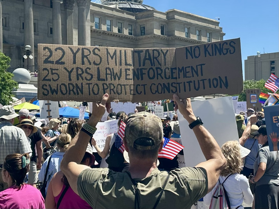 Man in drab green holding sign, “22 yrs military 25 yrs law enforcement sworn to protect constitution No Kings