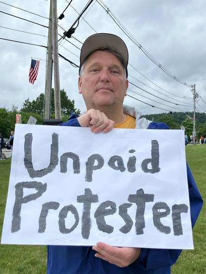 Picture of Dan holding a sign saying, "Unpaid Protester".