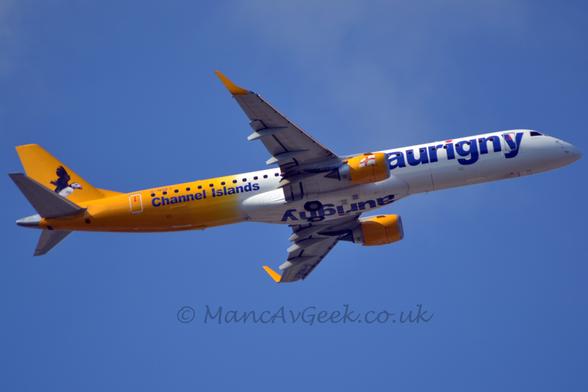 Low side view of a twin engined jet airliner flying from left to right at a very low altitude, with undercarriage stowed away, flaps extended from the rear of the wings, and the nose raised significantly, suggesting it has just taken off.
The plane is mostly white, with yellow tail and engine pods under the wings.
There are blue "Aurigny" titles in lower case on the forward fuselage, as well as under the wing root fairing on the belly.
There is additional blue text "Channel Islands" on the lower rear fuselage, under the registration "G-NSEY".
An image of a flying  black and white bird fills most of the tail.
Vivid blue sky fills the rest of the frame.
