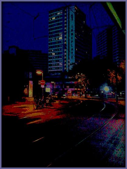 Stark mit Gimp bearbeitetes Foto des Ihmezentrums, prominent und zentral sichtbar das Haus Ihmeplatz 1, bei Nacht von der Bus- und Straßenbahnhaltestelle »Am Küchengarten«, Richtung stadteinwärts, aus fotografiert. Die Oberleitungen für die Straßenbahn sind gegen den schwach erleuchteten Himmel deutlich zu erkennen und scheinen den Himmel selbst zu strukturieren. Im Vordergrund auf der anderen Straßenseite eine Uhr mit Werbetafeln im Stil der Sechziger Jahre, Fahrräder, Menschen, die Schienen der Straßenbahn.