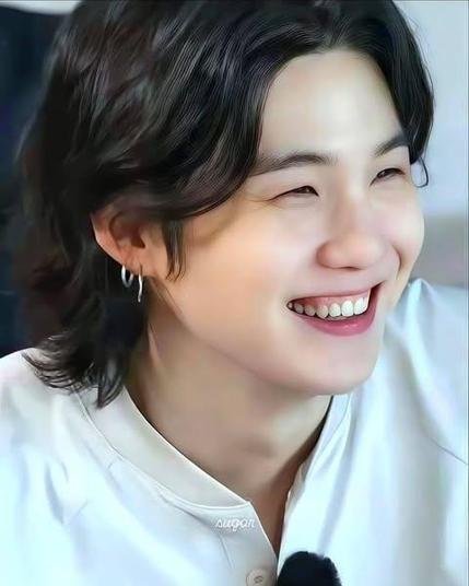 Suga of BTS in a white t-shirt, smiling. This is from the Run BTS aerial exercises episode.