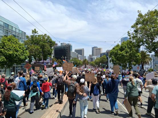 A crowd walking down tree-lined Market Street