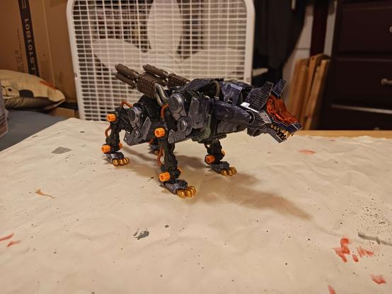 A photograph of the new Good Boy. Very few parts of him are unpainted and it really shows: the skeleton is black, the pipes on the exhaust are gunmetal, the armour is blue, and even the pipes on the backs of the legs are copper. This contrasts nicely against the bare orange plastic caps. The paint on the armour looks roughly sketched on, rather than brushed, which is frustrating to say the least.
