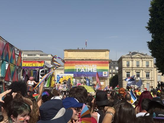 Photo d’une foule colorée. Au dessus un immense panneau Montpellier t’aime