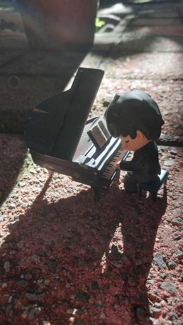 The Hirono The Pianist figure has a small grand piano, a musical score, a bench, and the Hirono figure playing the piano.
