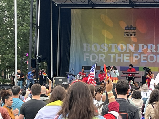 A similar shot from the crowd of the stage but angled left so you can see the ASL interpreters who are absolutely getting down, one is an African-American person with braids in a blue top, and the other is a lighter-skinned person with blond hair and a black t shirt.