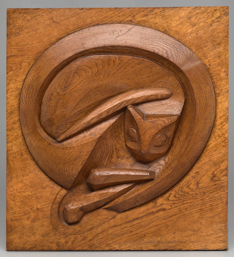 square block of oak wood with a circular carving of a curled-up cat in the center