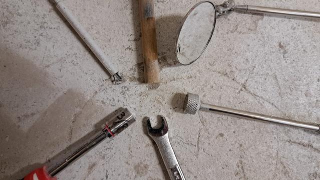 Some of the tools of the trade. From the top, then going clockwise:
- wooden dowel and double sided tape
- small mirror on telescoping shaft and multi-axis pivot
- magnet on telescoping shaft
- box end wrench with the outer surfaces of the jaws ground away
- socket (ground to a smaller outer diameter) on a hand driver
- flexible four-finger 'picker upper' to retrieve dropped parts