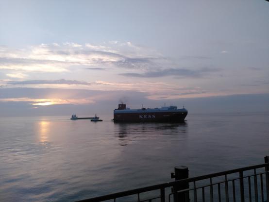 Ein Autotransporter mit Achterschlepper und ein Kümo vor dem Sonnenaufgang