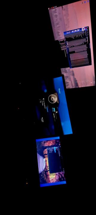 The photograph composed in total pitch black darkness, shows a computer setup with multiple screens displaying various interfaces. The top screen displays a music player interface with a list of tracks and a waveform, set against a background image of a cityscape at dusk. The middle screen shows a music library or playlist with a blue header and a circular control element, possibly for playback. The bottom screen features a music player interface with a colorful background image, displaying a list of tracks and playback controls. The screens are arranged in a staggered layout, with the top screen tilted to the right, the middle screen centered, and the bottom screen tilted to the left. The overall color scheme includes blues, purples, and warm tones from the background images.

 Ovis2-8B

🌱 Energy used: 0.175 Wh