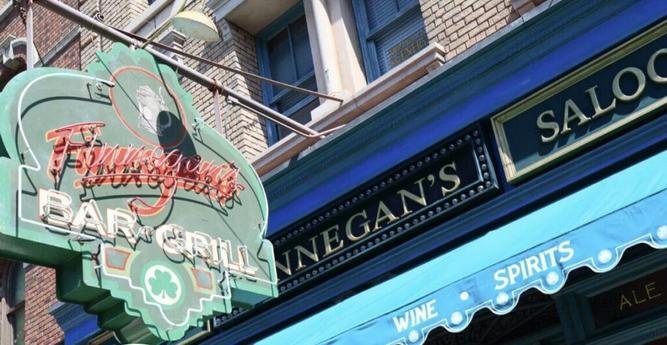 A vintage "Finnegan's Bar & Grill" sign at Universal Studios Japan hangs above a storefront with blue awning and "Saloon" sign.