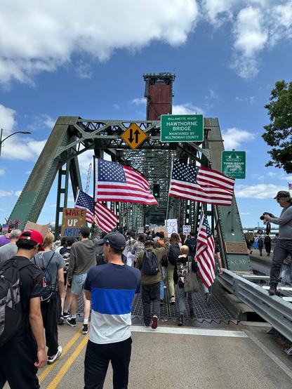 Marching across the Hawthorne Bridge. Visible protest signs read "Wake Up America," "Black Lives Matter" and "I Love L.A." with several American flags. "ACAB" is written on the bridge itself