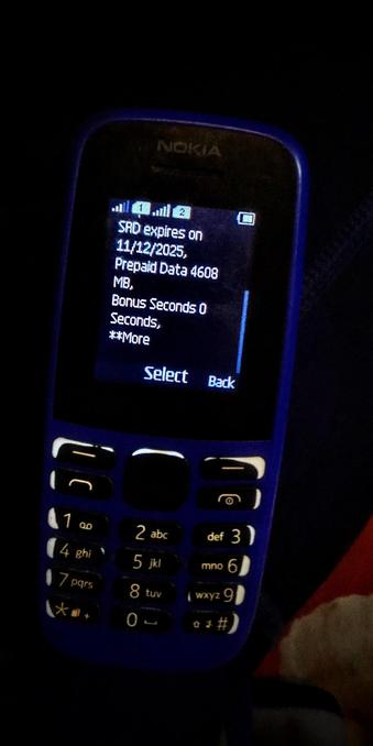 The photograph shot in total absolute darkness, shows a close-up of a blue Nokia mobile phone. The phone's screen displays information about prepaid data and bonus seconds. The text on the screen reads: "SRD expires on 11/12/2025, Prepaid Data 4608 MB, Bonus Seconds 0 Seconds, **More." Below the text, there are two buttons labeled "Select" and "Back." The phone's keypad is visible, featuring the standard numeric layout with letters above the numbers, and additional function keys such as "Call," "End Call," and "Menu." The phone's screen is illuminated, and the background is dark, making the phone stand out. The phone is placed on a surface with a red and white object partially visible in the bottom right corner.


 Ovis2-8B

🌱 Energy used: 0.195 Wh