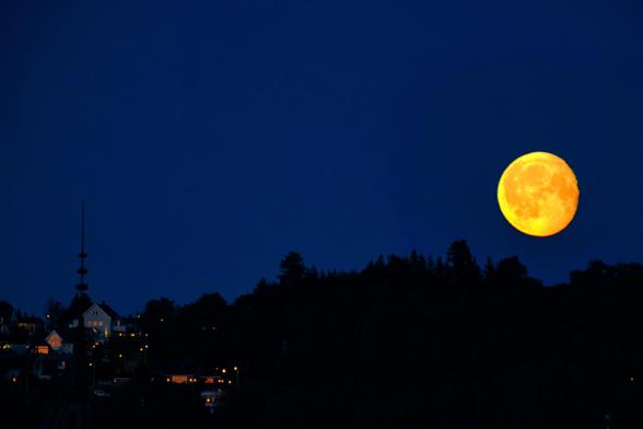 The moon rising over a darkened silhouette of a hill. A few homes are visible on the hill.

Photo taken with a Fujifilm X-T30II + Fujinon XF70-300mm f4-5.6 telephoto lens.