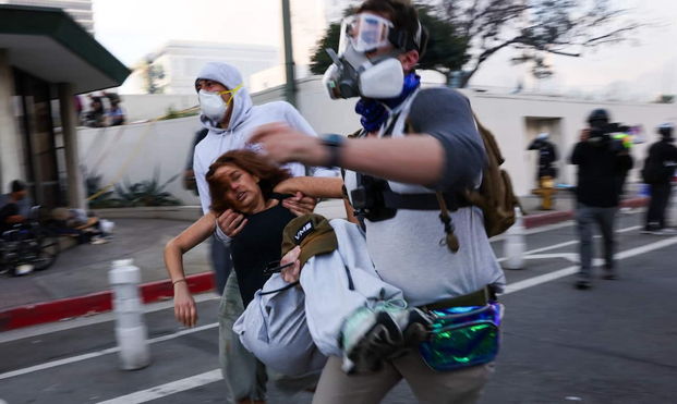 An injured woman is carried off as protesters clash with law enforcement outside the federal building complex in downtown Los Angeles on Saturday. (Spencer Platt/Getty Images)