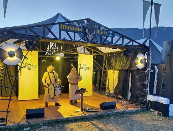 Two masked musician in medieval bee keepers clothing. They have a basket like thing in front of the face.