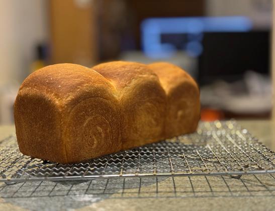 A triple domed sandwich loaf on a cooling rack. The side of each dome features a swirl.