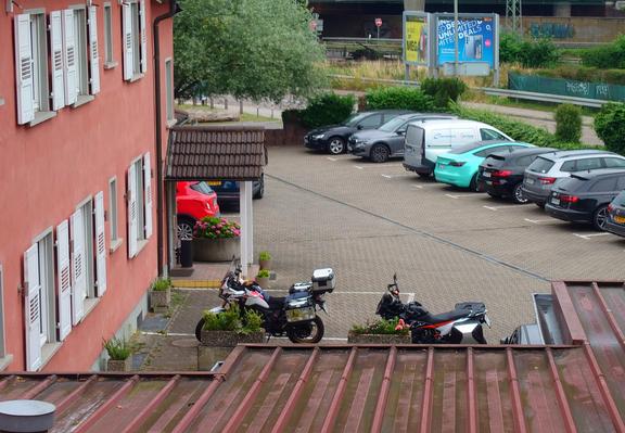 view to a parking in front of a hotel. 2 motorcycles are in the center of the photo