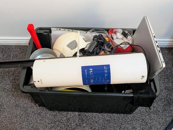 A plastic box containing assorted field gear