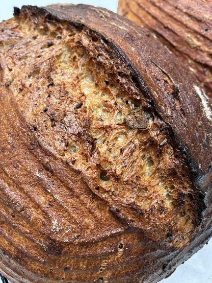 Golden brown sourdough showing gluten strands and seeds.