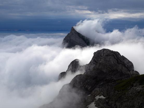 Aus der tief liegenden Wokendecke ragen die Gipfel des Alpsteins teilweise heraus, im Hintergrund ist dunkel der Alpenhauptkamm zu erkennen.