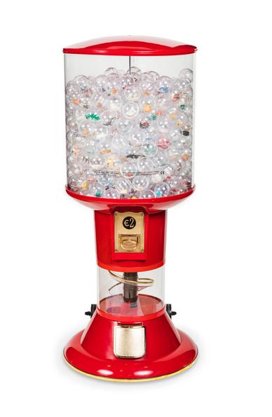 We see a large red vending machine filled with transparent balls containing coloured toys. The upper part of the vending machine is transparent so that all the balls inside can be seen.