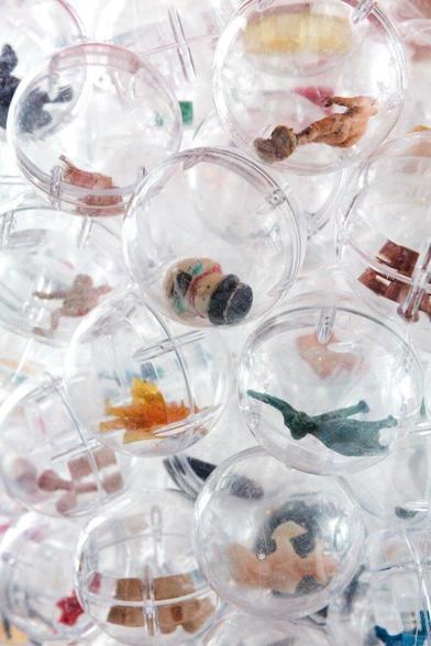 The picture is a close-up of transparent plastic balls that can be seen inside a vending machine. The balls contain different coloured plastic toys.