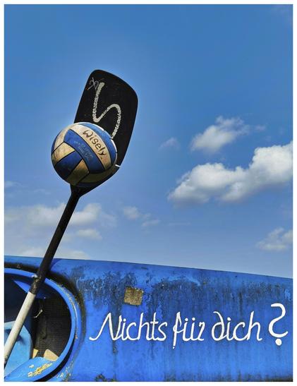 Das Bild zeigt einen Paddel mit einem handballgroßen Volleyball darauf, der auf einem blauen, quer liegenden Kajak am unteren Bildrand ruht. Auf dem Kajak steht in weißer Schrift „Nichts für dich?“. Der Hintergrund ist ein blauer Himmel mit ein paar weißen Wolken.