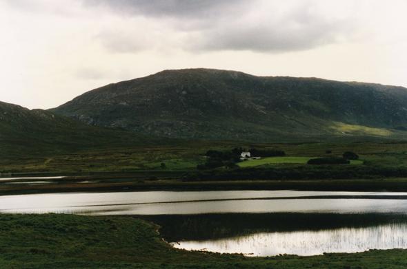Étang dans la région du Kerry en Irlande, avec une lumière déclinante de fin d'après-midi et des collines verdoyantes derrière.