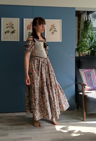 The same woman wearing the dress and the corset. She is mid-movement which shows the flow of the long dress.