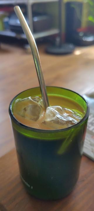 Ijskoffie met ijsklontjes en een metalen rietje in een groen glas
