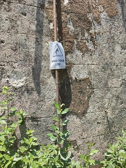 Picture of a warming for minding your steps, placed on a wall.