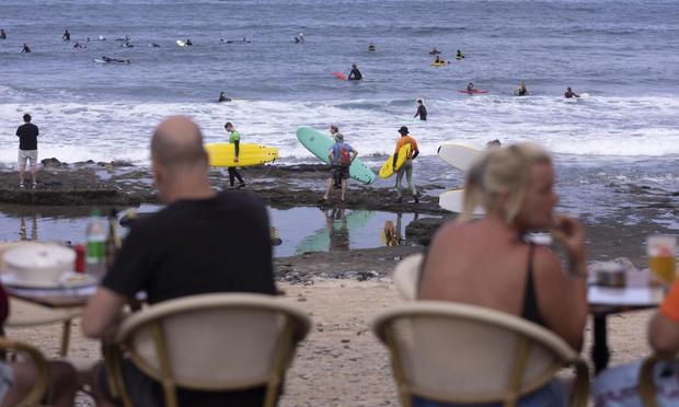 Turistas disfrutan del buen tiempo en la zona turística del municipio de Arona, al sur de la isla de Tenerife. (EFE/ Miguel Barreto)