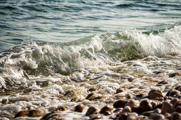 Ein Kieselstrand an den Wellen schwappen. Und beim Ablaufen hat man ein Rollen im Ohr.