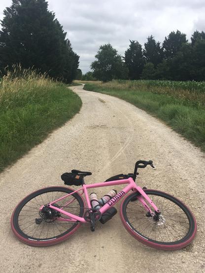 Mon vélo de gravel Guava Spot rose couché au milieu d’une large piste de gravier blanc