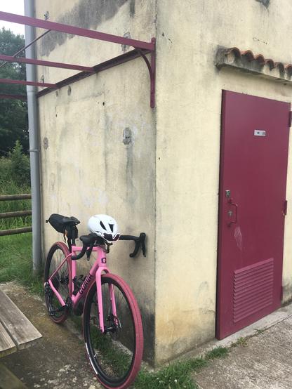 Mon vélo de gravel Guava Spot rose posé contre la station VNF vignettes de stationnement/toilettes d’Escatalens