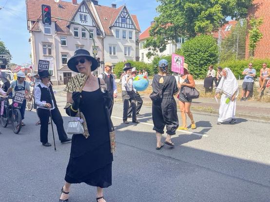 Menschen auf der Straße verkleidet als Milliardäre. Die mit einer aufgeblasenen Weltkugel spielen.