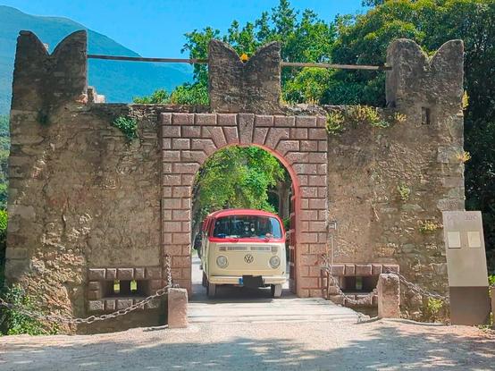 VW T2 fährt durch Ausfahrt mit schmalem, steinernem Torbogen.