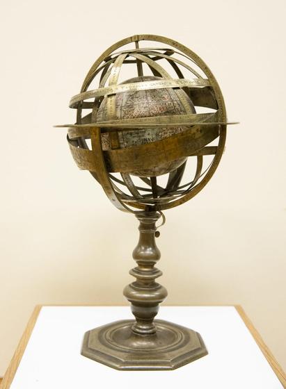 A small globe on a stand surrounded by engraved brass rings