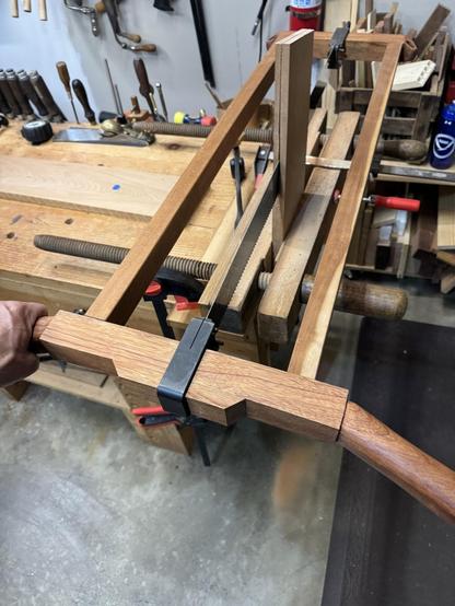 A frame saw on a workbench resawing a cherry board.