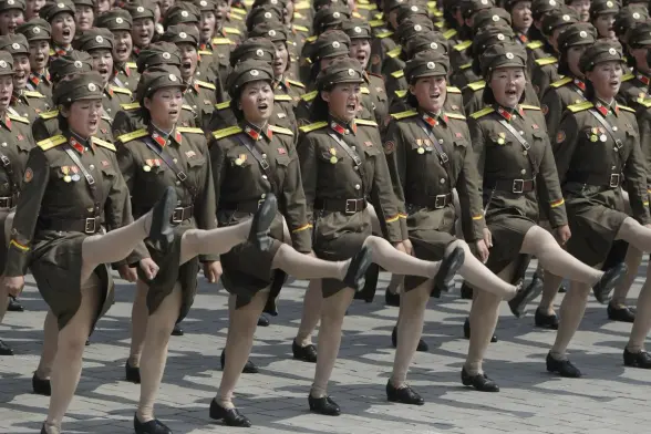 A military formation comprising exclusively female soldiers in dark brown uniforms marching on parade.   Their right legs are high-kicking - one might say goose-stepping. 

Okay, they're not US soldiers but North Korean. Hell, one dictator looks just like another... 

But good to see the D.P.R.K. doesn't pander to the D.E.I. brigade, what?