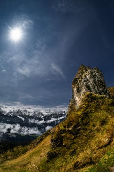 Hochformatfotografie im Gegenlicht eines geneigten Felsens. Im Hintergrund sind die Berner Alpen.