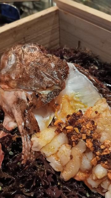 O cabracho, ca sua cabeza e espiñas, nunha caixa, co peixe en cru, cortado sobre a espiña