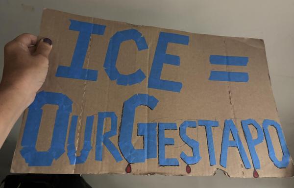 My cardboard sign for yesterday’s protest. Blue masking tape for the letters. “ICE = Our Gestapo” but Gestapo is the only word with black shadows, and three drops of blood (black ink pen and red lipstick).