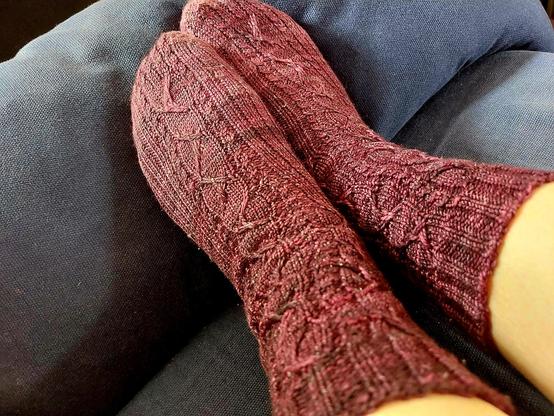 Pair of socks with a meandery pattern of elongated yarnovers. They form a curve on top of a triangular bit, very clever. Reminds me a little of flames.