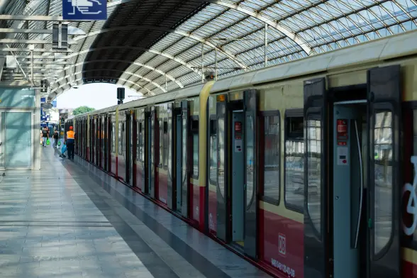 a type 481/482 s-bahn is standing in berlin spandau, an s-bahn and mainline rail station. the sun is shining through the glass roof