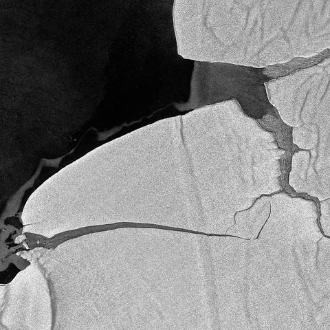 An abstract black and white image featuring textured surfaces and subtle cracks. The composition showcases contrasting areas of light and shadow, creating a dynamic interplay of shapes and lines.