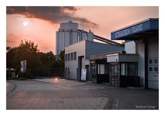 A sunset over some buildings on an industrial estate with a pink red sky.