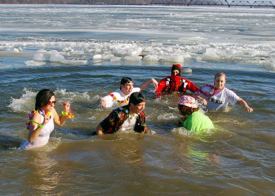 Participants in the water during a polar bear plunge when there is ice on the water.